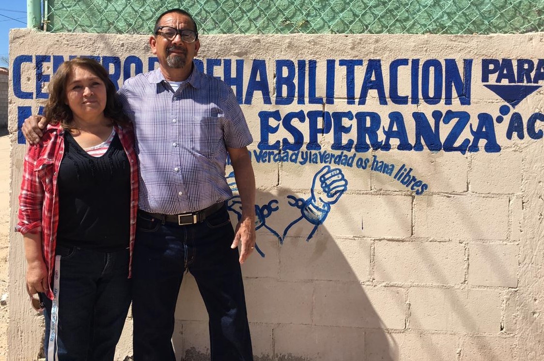Pastor Jose & Pastora Ana in front of Rehabilitacion Sign